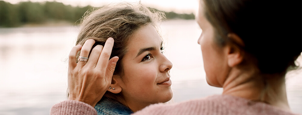 Eine Frau streicht ihrer Tochter übers Gesicht. 