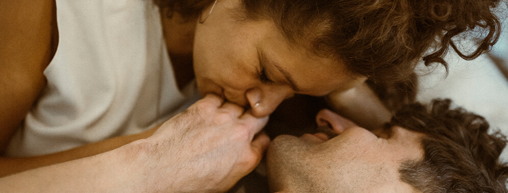 Ein Pärchen liegt kuschelnd im Bett. 