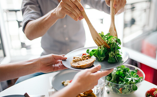 Ein Teller wird mit Salat gefüllt.