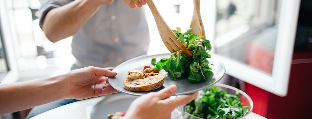 Ein Teller wird mit Salat gefüllt.