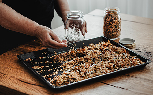 Müsli wird auf einem Backblech verrührt.
