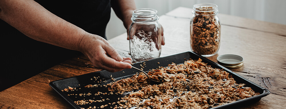 Müsli wird auf einem Backblech verrührt.