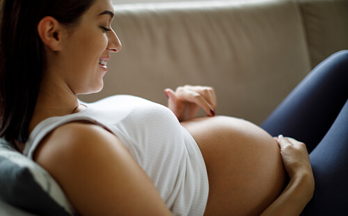 Eine schwangere Frau berührt ihren Bauch.