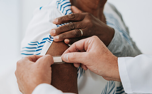 Ein Pflaster wird nach einer Impfung auf den Oberarm geklebt.