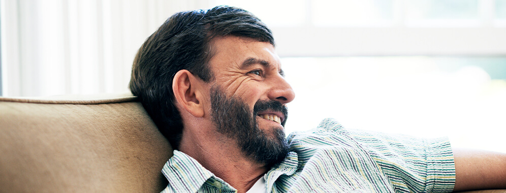 Ein Mann liegt lächelnd auf dem Sofa. 