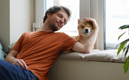 Ein Mann streichelt einen Hund.