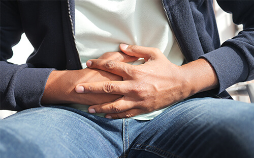 Zwei Hände halten den Bauch fest, scheinbar hat die Person Bauchschmerzen.