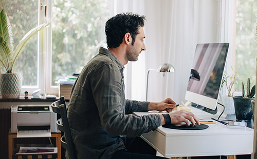 Ein Mann sitzt an seinem Arbeitsplatz am Computer.
