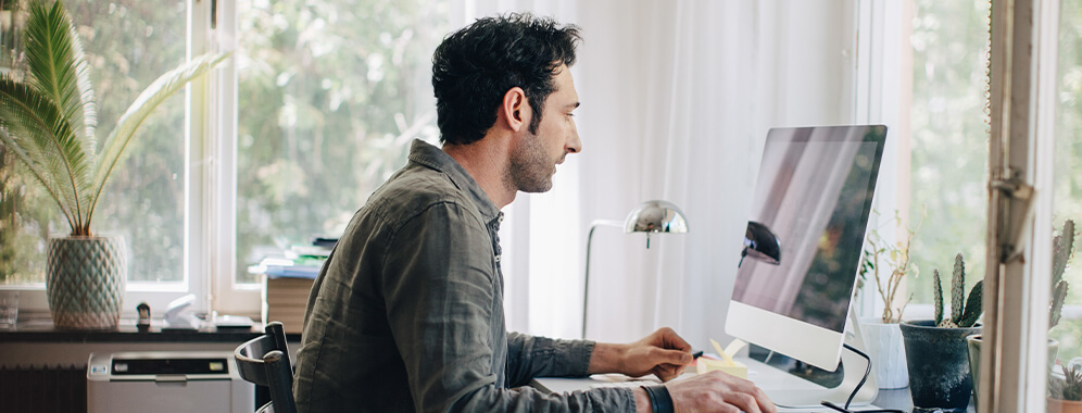 Ein Mann sitzt an seinem Arbeitsplatz am Computer.