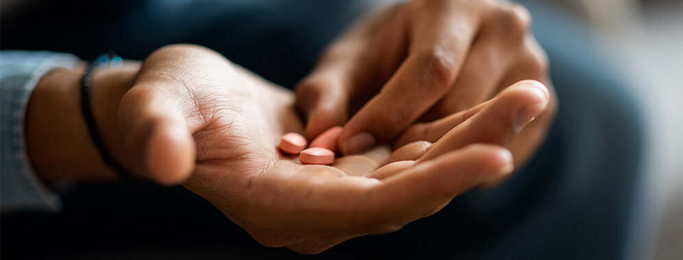 Das Bild zeigt männliche Hände mit ein paar Tabletten.