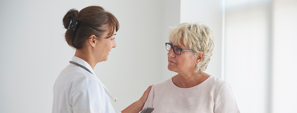 Eine Ärztin legt beruhigend den Arm auf die Schulter einer MS-Patientin und spricht mit ihr. 