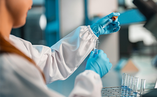 Eine Laborantin hantiert mit Pipette und Reagenzglas.