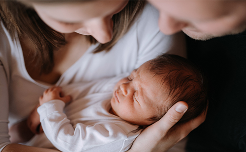 Eine Frau mit MS hält ein Baby im Arm. 