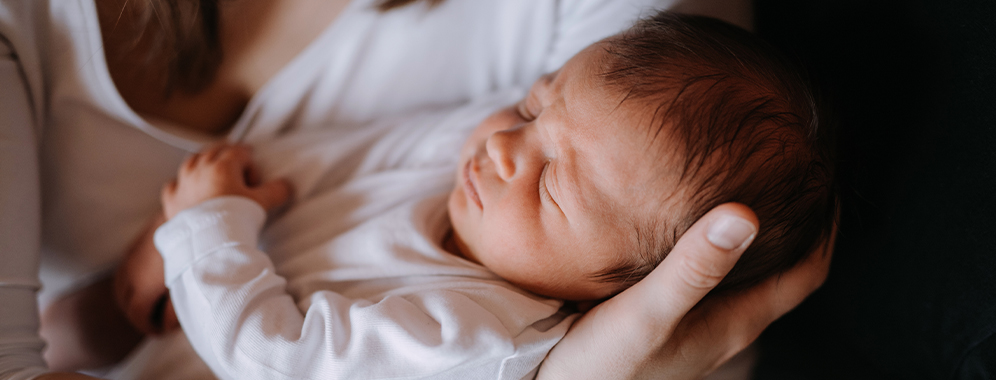 Eine Frau mit MS hält ein Baby im Arm.