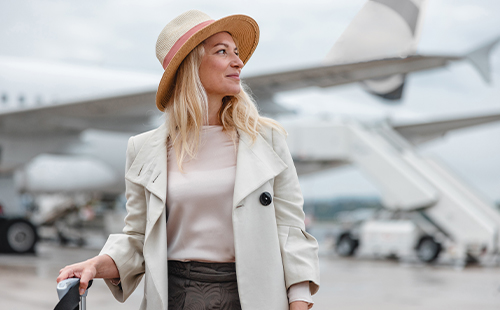 Eine Frau mit MS steht vor einem Flugzeug.