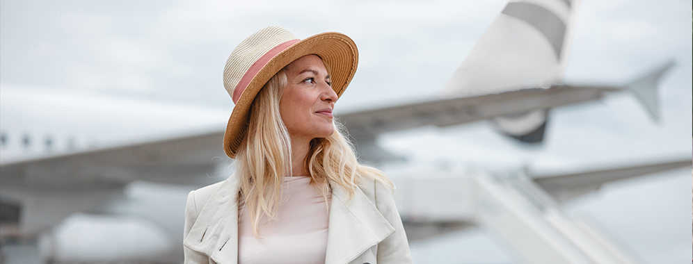Eine Frau mit MS steht vor einem Flugzeug.