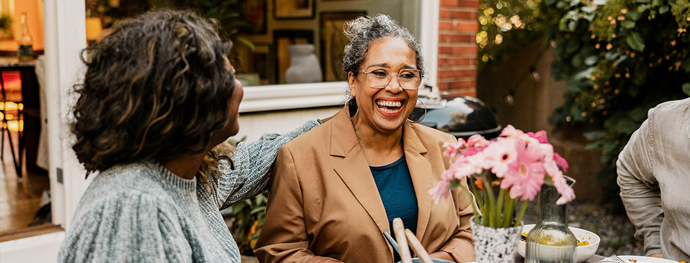 Zwei Frauen sitzen in einem Café und lachen miteinander.