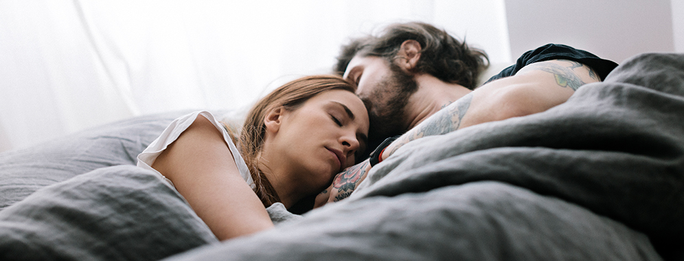 Eine Frau mit MS liegt schlafend neben ihrem Partner im Bett und schläft.