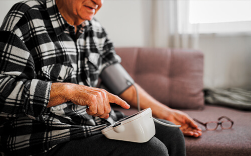 Ein Mann misst sich mit einem Messgerät den Blutdruck. 