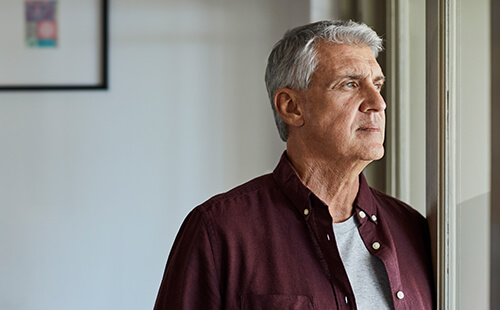 Ein älterer Herr schaut nachdenklich aus dem Fenster.