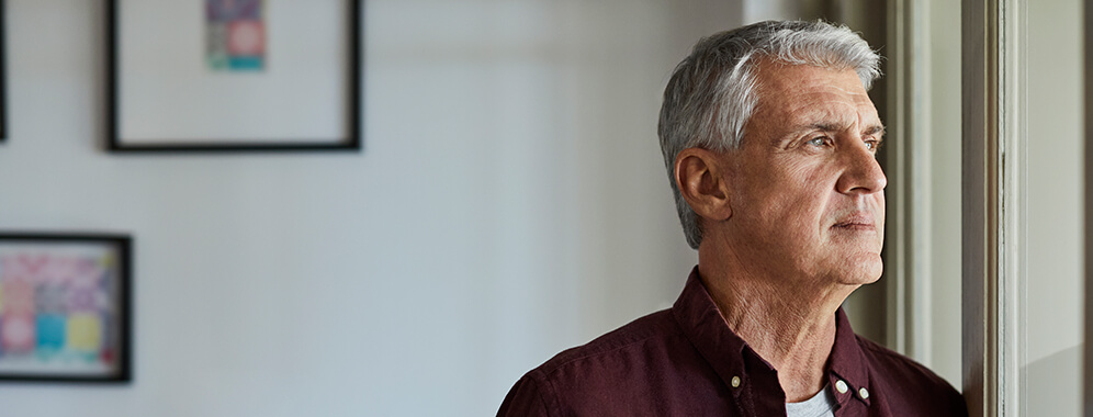 Ein älterer Herr schaut nachdenklich aus dem Fenster.
