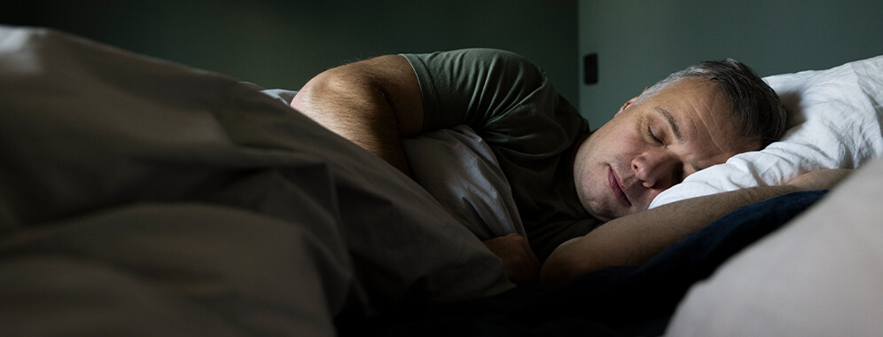 Ein Mann mit Psoriasis schläft friedlich im Bett.