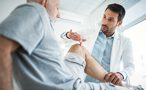 Eine Person wird am Bein vom Arzt untersucht. 