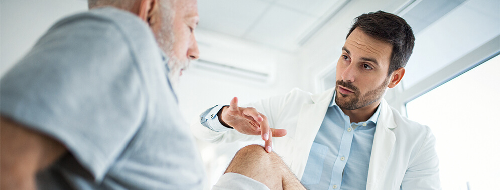 Ein Mann lässt sein Knie beim Arzt untersuchen. 