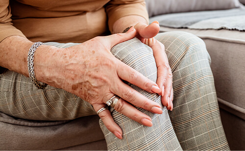 Eine Frau hält sich das Knie. 