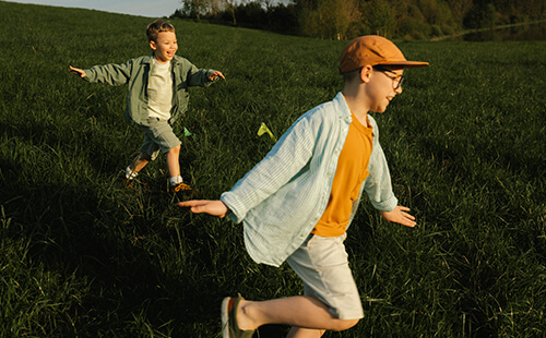 Zwei Jungen laufen über eine Wiese.