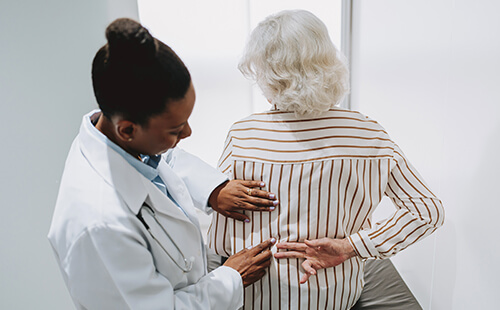 Eine Ärztin untersucht den Rücken einer Frau. 