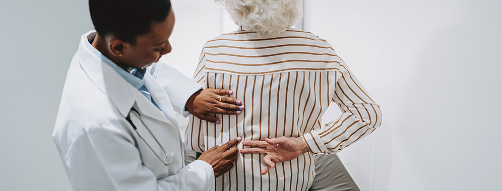 Eine Ärztin untersucht den Rücken einer Frau.