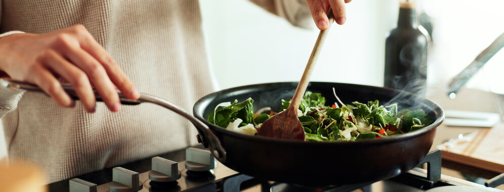 Eine Frau kocht Gemüse am Herd.