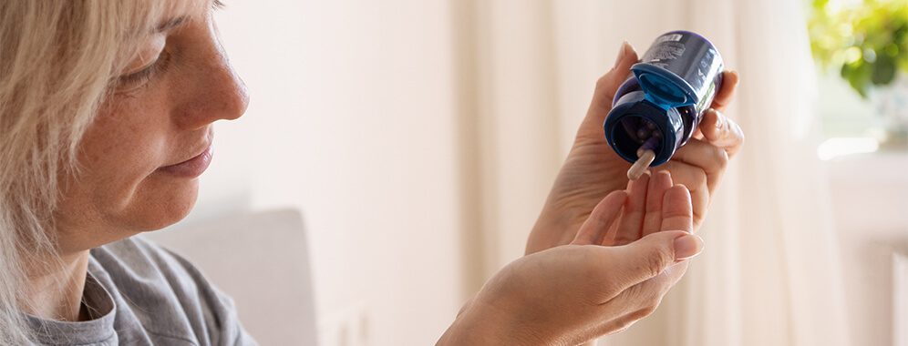 Eine Frau nimmt Tabletten aus einer Dose.