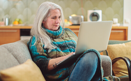 Eine Frau mit Laptop auf dem Sofa.