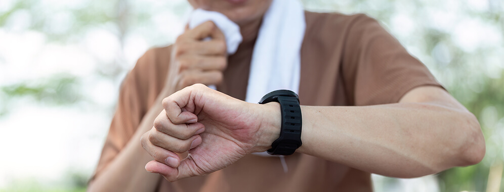 Ein Mann guckt beim Sport auf seine Sportuhr. 
