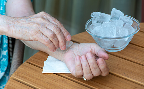 Eine Person kühlt das Handgelenk mit Eiswürfeln