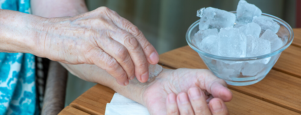 Eine Person kühlt sein Handgelenk mit Eiswürfeln. 