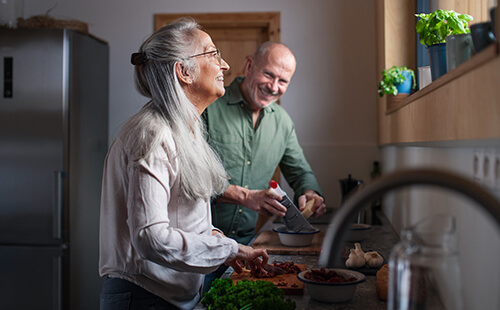 Zwei Personen kochen und lachen zusammen. 
