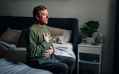 Ein Mann hält sich die Hände vor die Brust. 