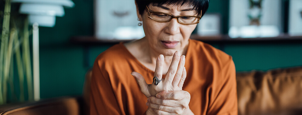 Eine Frau hält ihre scheinbar schmerzende Hand. 