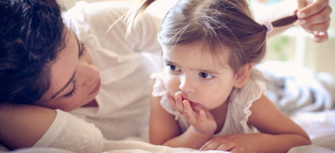 Mutter und Kind. Kind mit Zöpfen, Mutter schaut Kind an.