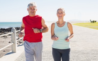Zwei Personen joggen auf einem Weg am Meer. Sportkleidung.