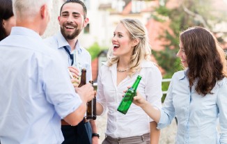 Gruppe von Menschen, die im Freien mit Getränken anstoßen und lachen.