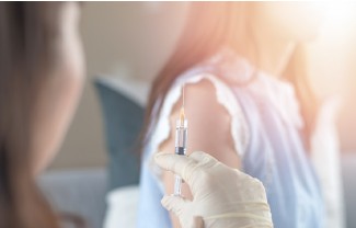 Nahaufnahme einer Hand, die eine Spritze in einen Arm injiziert.