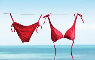 Roter Bikini, der an einer Leine vor blauem Meer und Himmel hängt.