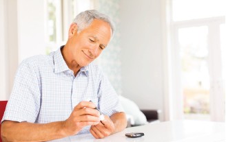 Älterer Mann, der sich in den Finger sticht, um seinen Blutzucker zu messen.