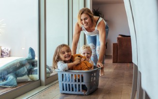 Frau mit Kindern in einer Wäschetruhe. Lächeln. Innenraum.
