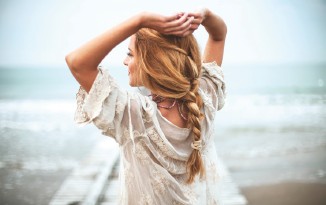 Frau am Meer, Zopf, Spitze-Kleid, Rückenansicht.