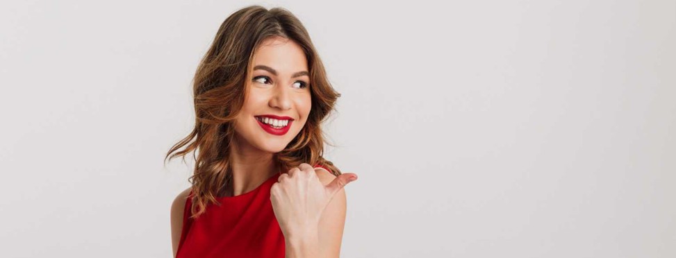 Lächelnde Frau zeigt mit dem Finger nach rechts.